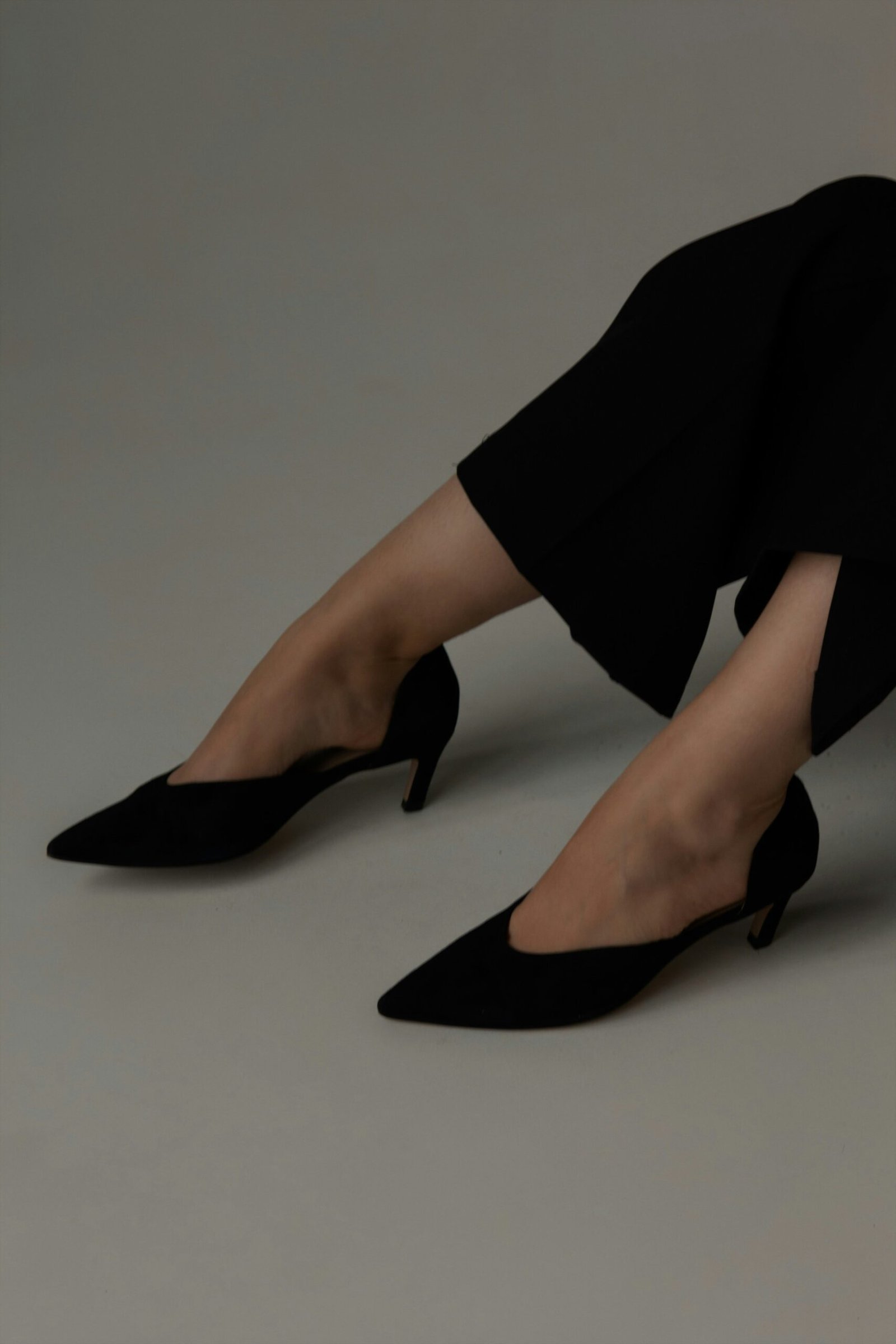 Black pointed-toe kitten heels worn with black trousers.